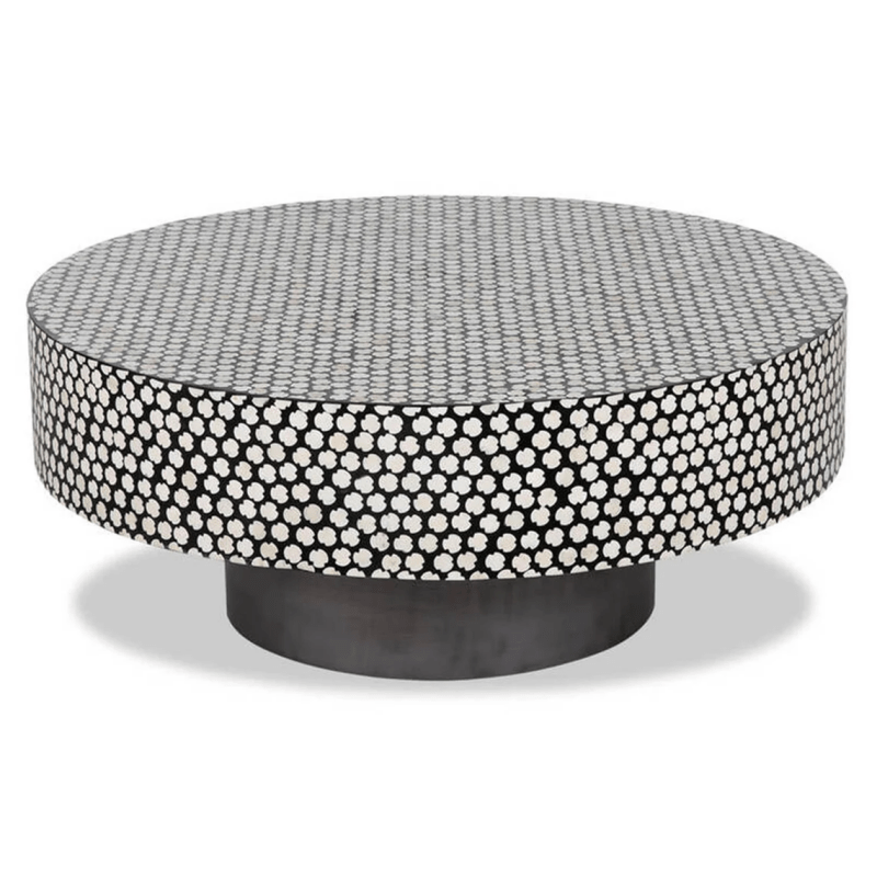 Round drum-shaped black and white bone inlay coffee table with clover polka dot motif and dark metal plinth base on white background