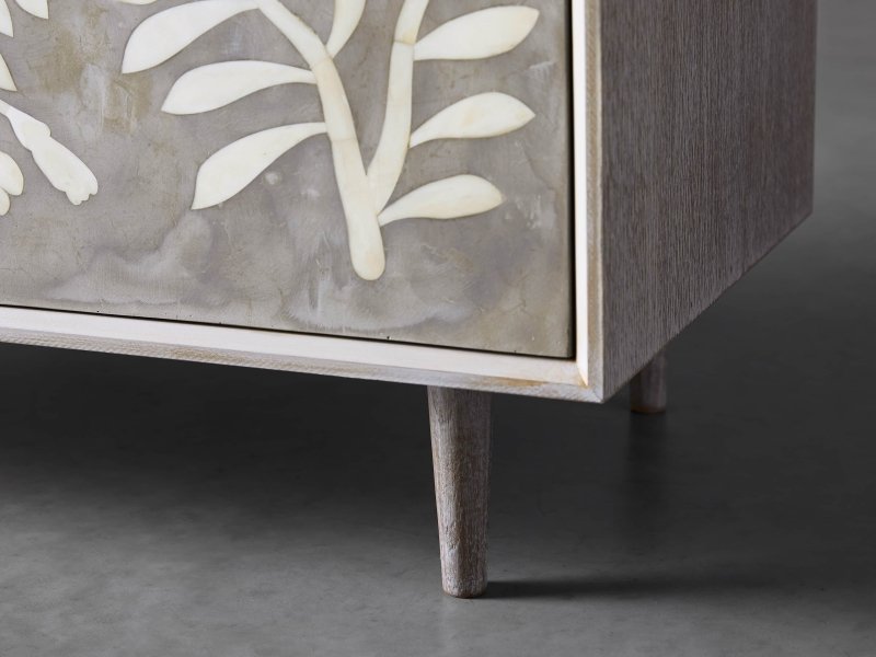 Detail of tapered solid wood leg and lower door panel of charcoal bone inlay cabinet, showing ivory leaf inlay and wood grain texture
