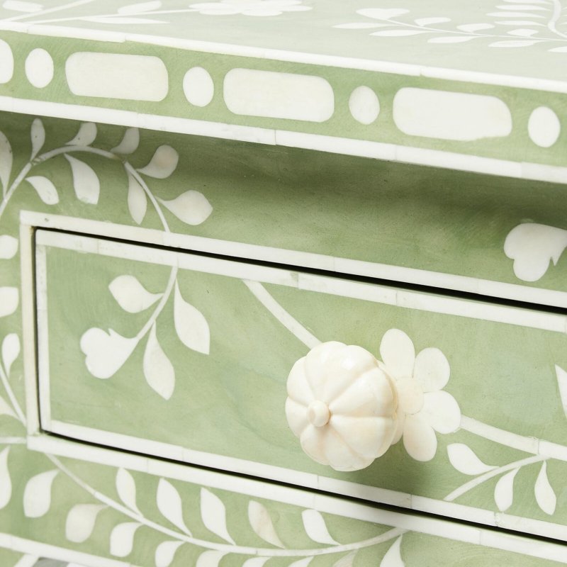 Close detail of a carved white bone flower knob and hand-inlaid floral vine pattern on the drawer front of a sage green bone inlay console table