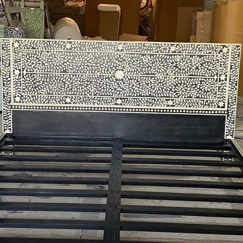 Close detail of bone inlay floral pattern on black headboard showing hand-cut ivory leaf swirls and star medallion inlay work