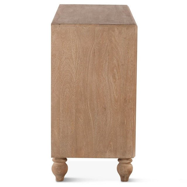 Angled side view of a natural mango wood lowboy showing carved floral drawer fronts, side panel depth and bun feet