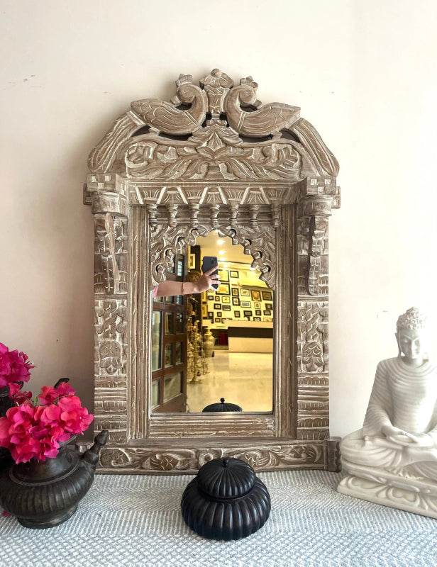 Floral Jharokha Framed Mirror in rustic solid wood, front view with pink flowers, a black vessel and white seated statue.
