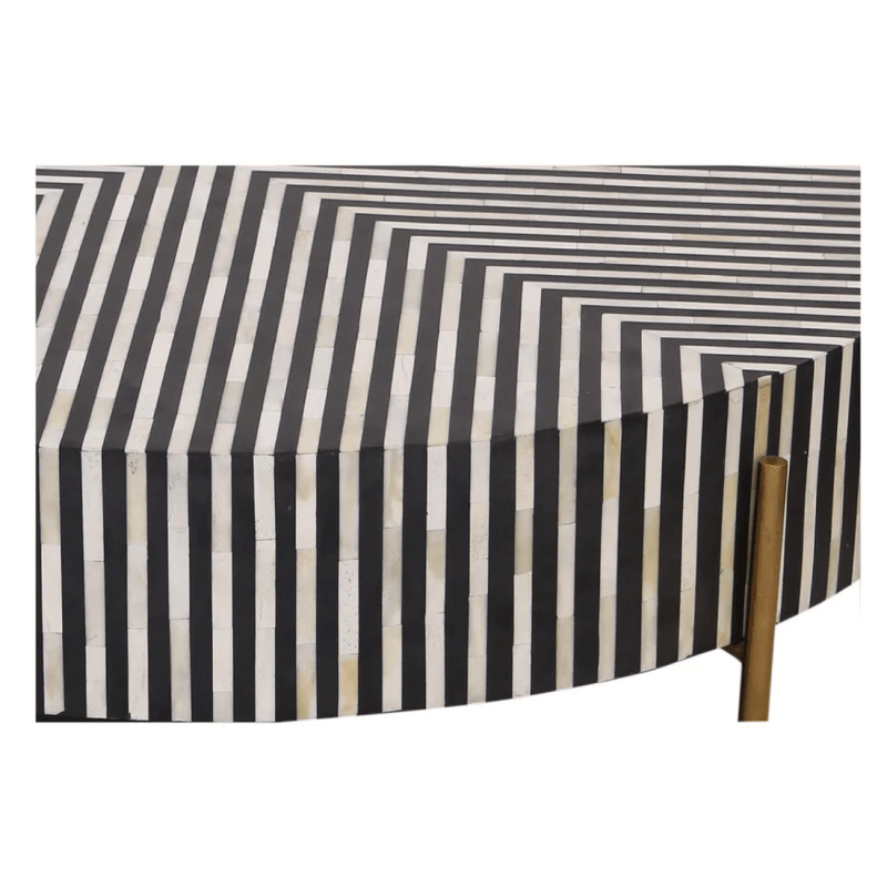 Close detail of black and white diagonal stripe bone inlay pattern on a handmade round coffee table surface with brass leg visible