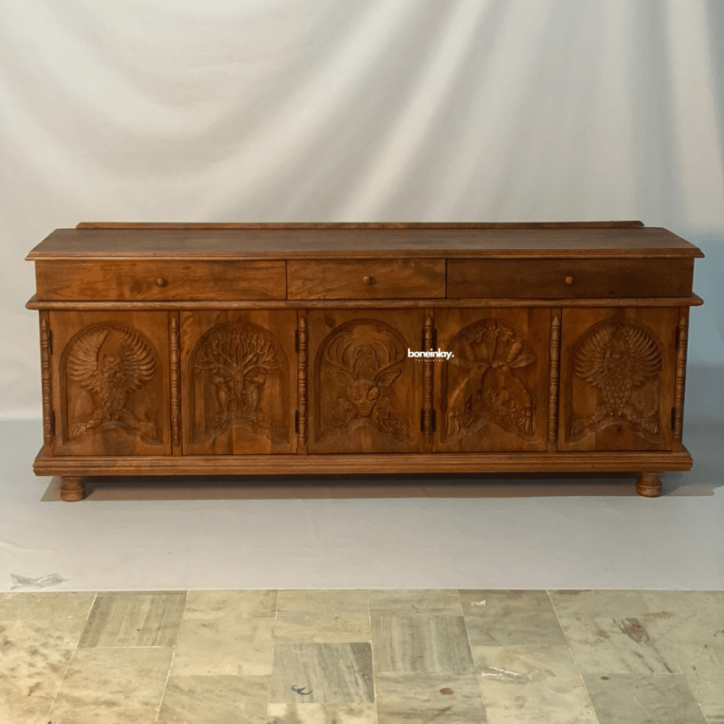 Hand carved menagerie media unit in a front view, with warm natural wood, five animal relief doors and three drawers.