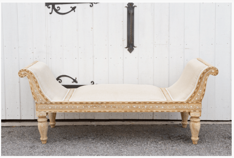 Traditional wood inlay teak upholstered chaise lounge with geometric bone inlay frame and turned legs against white barn door