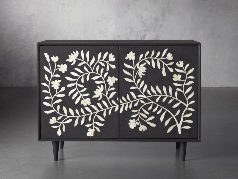 Handcrafted bone inlay charcoal botanical cabinet with ivory leaf and blossom pattern on doors, tapered wooden legs, neutral backdrop