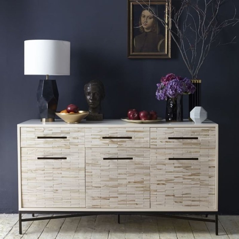 Handmade bone inlay credenza with whitewash tiled facade and black trestle metal legs styled against a dark navy wall with decorative accessories