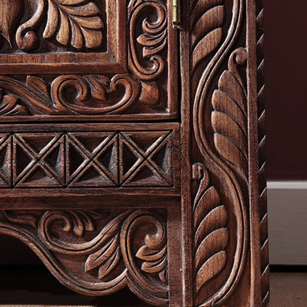 Leaf carved wooden cupboard in brown solid wood, corner detail view showing scrolling leaves and crosshatched trim.