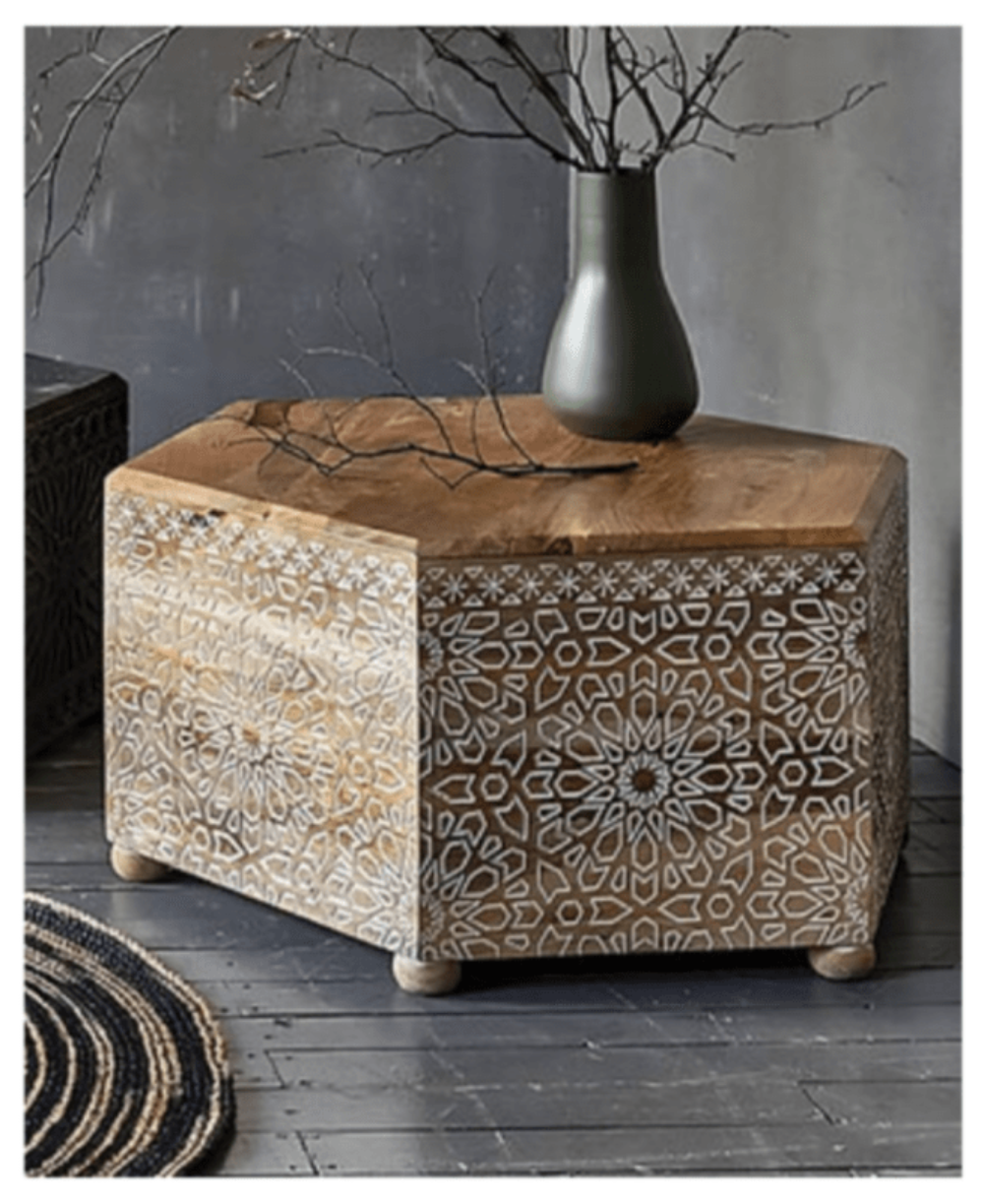 Light wood Albaron accent table in a front view, showing its carved face and decorative objects on top.