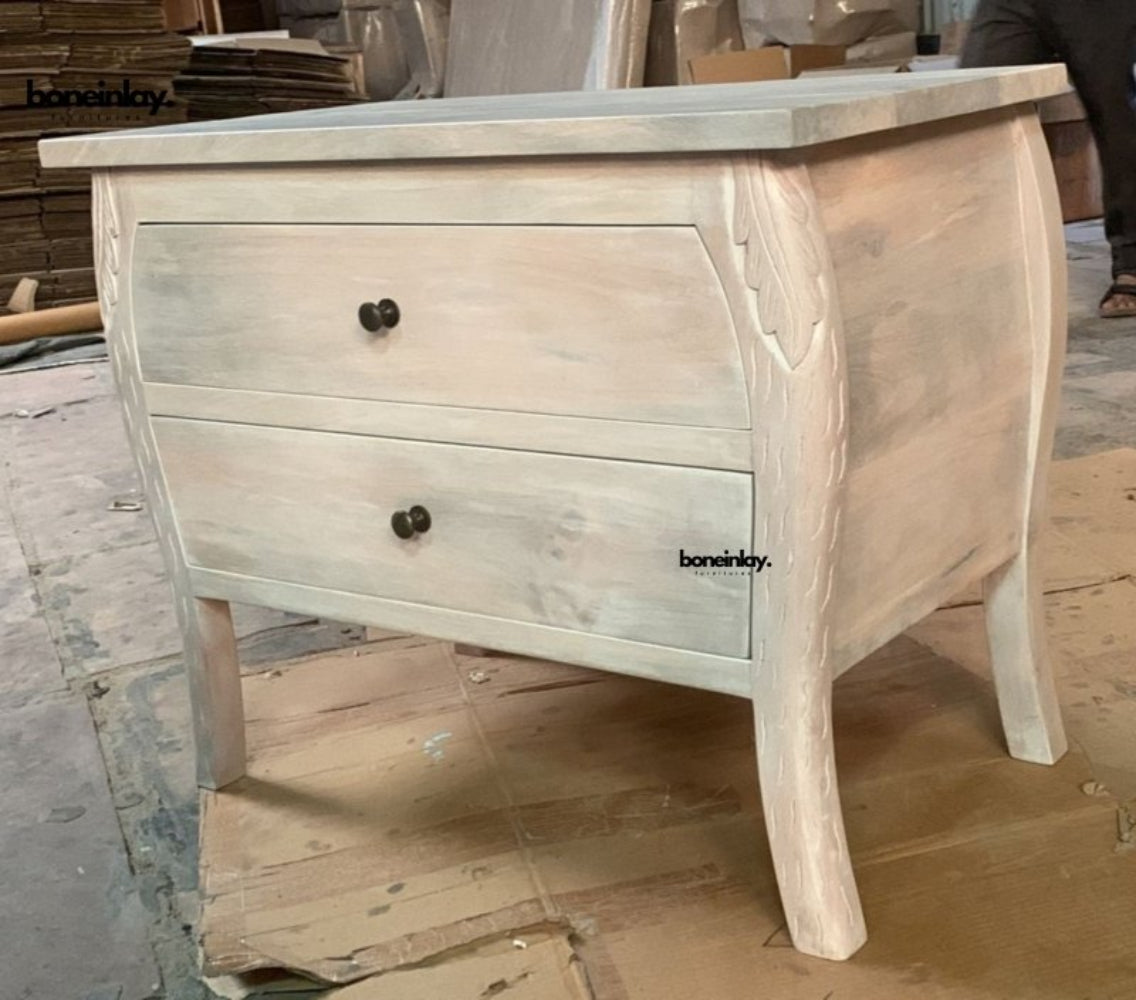 Menagerie two-drawer bedside table in a pale finish, shown from the front with dark knobs and tapered legs.