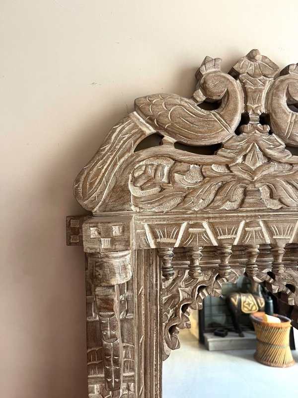 Peacock Crest Accent Mirror in rustic carved wood, corner detail view showing a bird relief and scalloped arch.