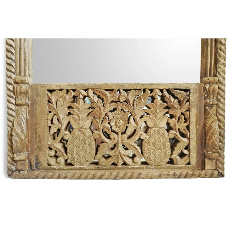 Pineapple carved accent mirror in rustic wood, base detail view showing paired fruit motifs and a central flower.