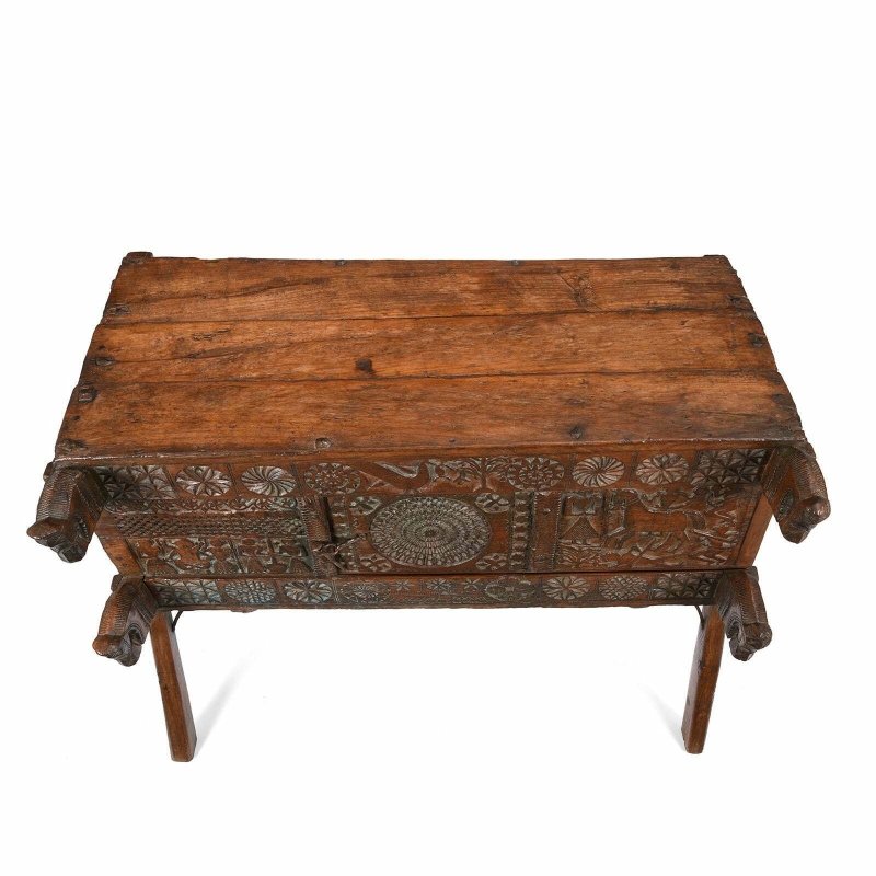 Rectangular wood dowry chest in natural walnut finish, top view showing broad wooden planks above carved panels.