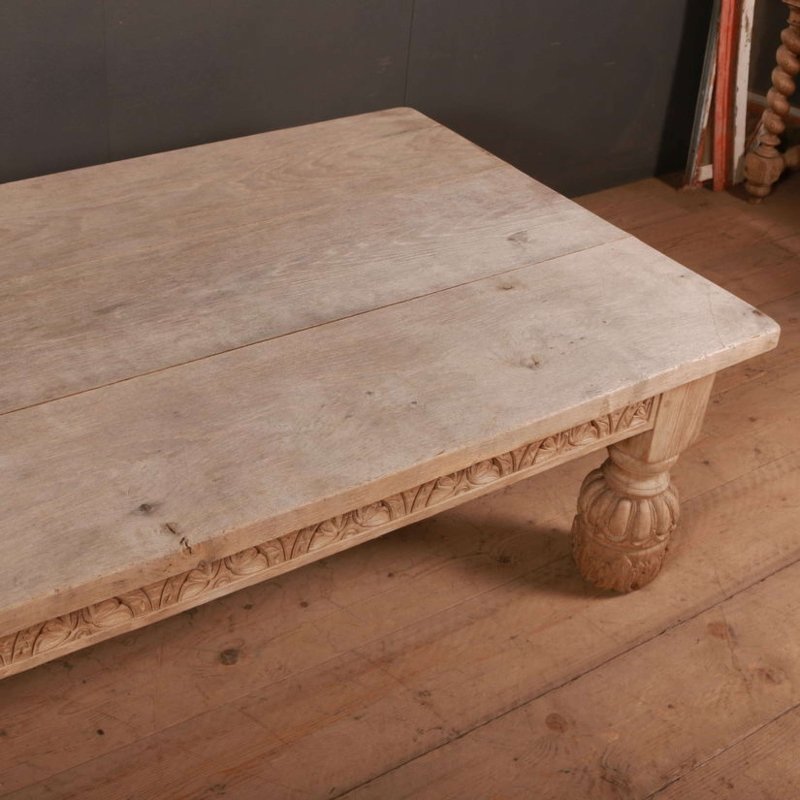 Rectangular wood occasional table with a pale, lightly marked top and carved edge, viewed from an elevated corner angle.