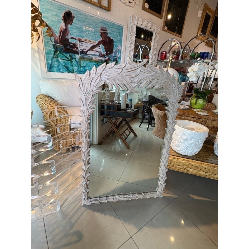 Rustic leaf accent mirror with a carved wood surround, front view beside a white planter with woven seating behind.
