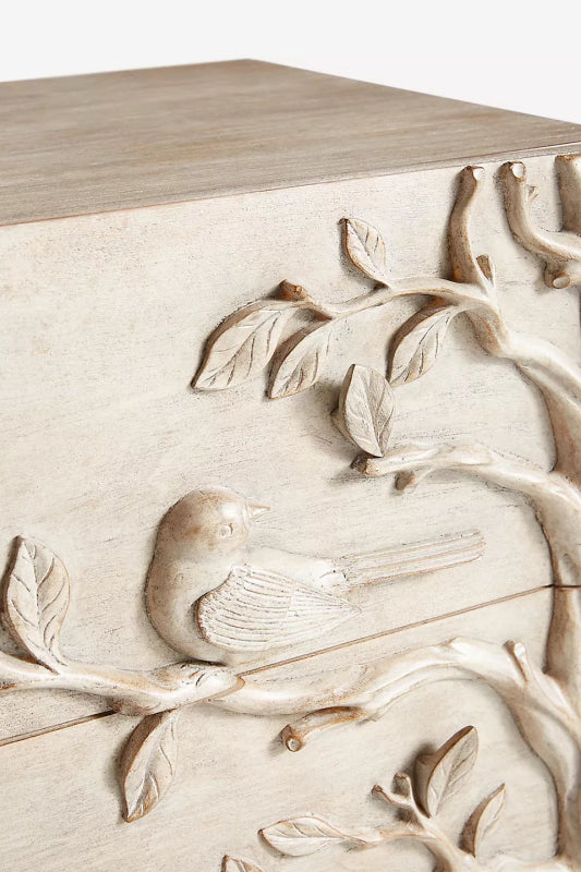 Close-up of Hand-carved lowboy in washed-grey wood, with three drawers and a continuous bird-and-foliage design.