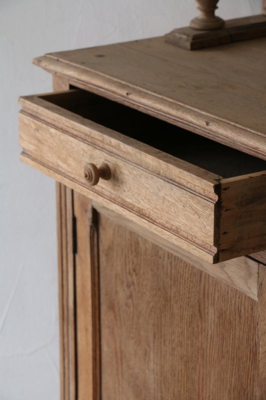 Wooden buffet with a partially open top drawer, angled close-up of the drawer opening and paneled cabinet front.