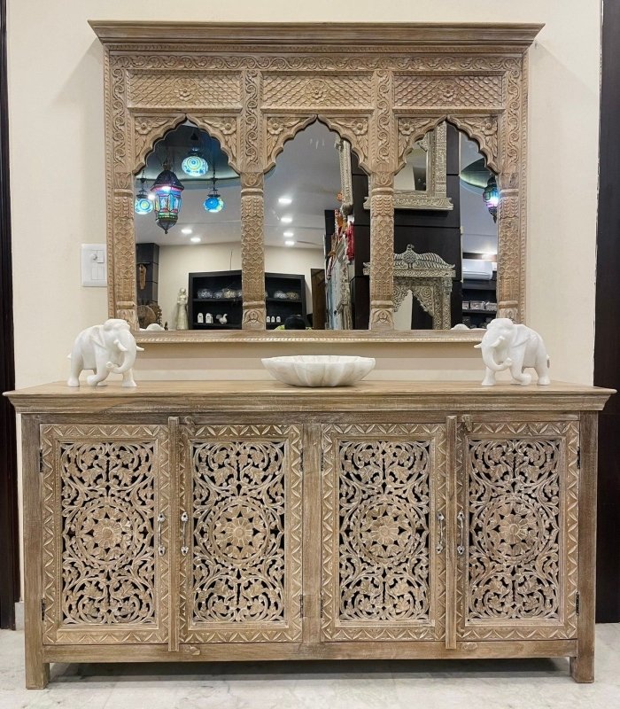A matching set of a hand-carved Indian Jharokha wall mirror and a solid wood four-door sideboard with intricate floral and mandala carvings in a natural finish.