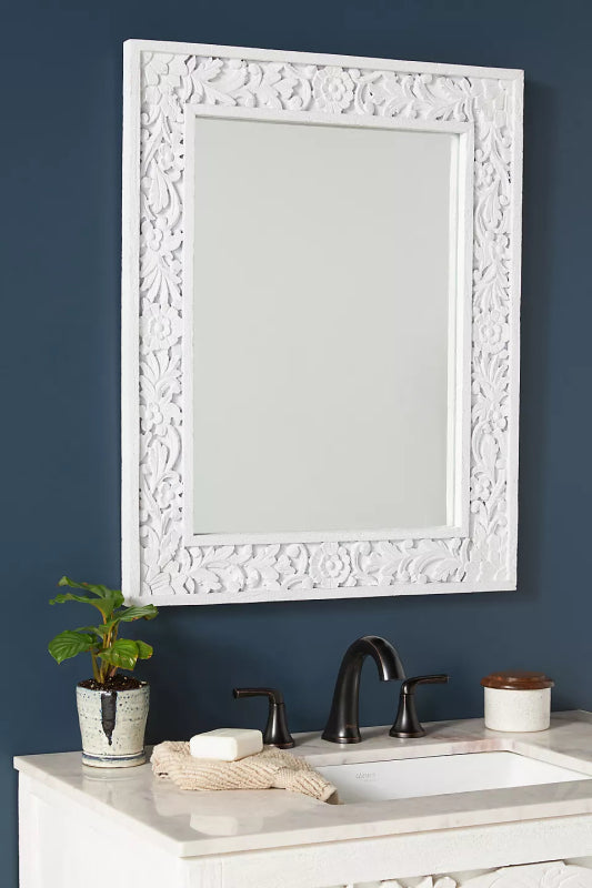 Rectangular wall mirror with a solid wood frame featuring intricate, deep-relief floral carvings in a white-washed finish.