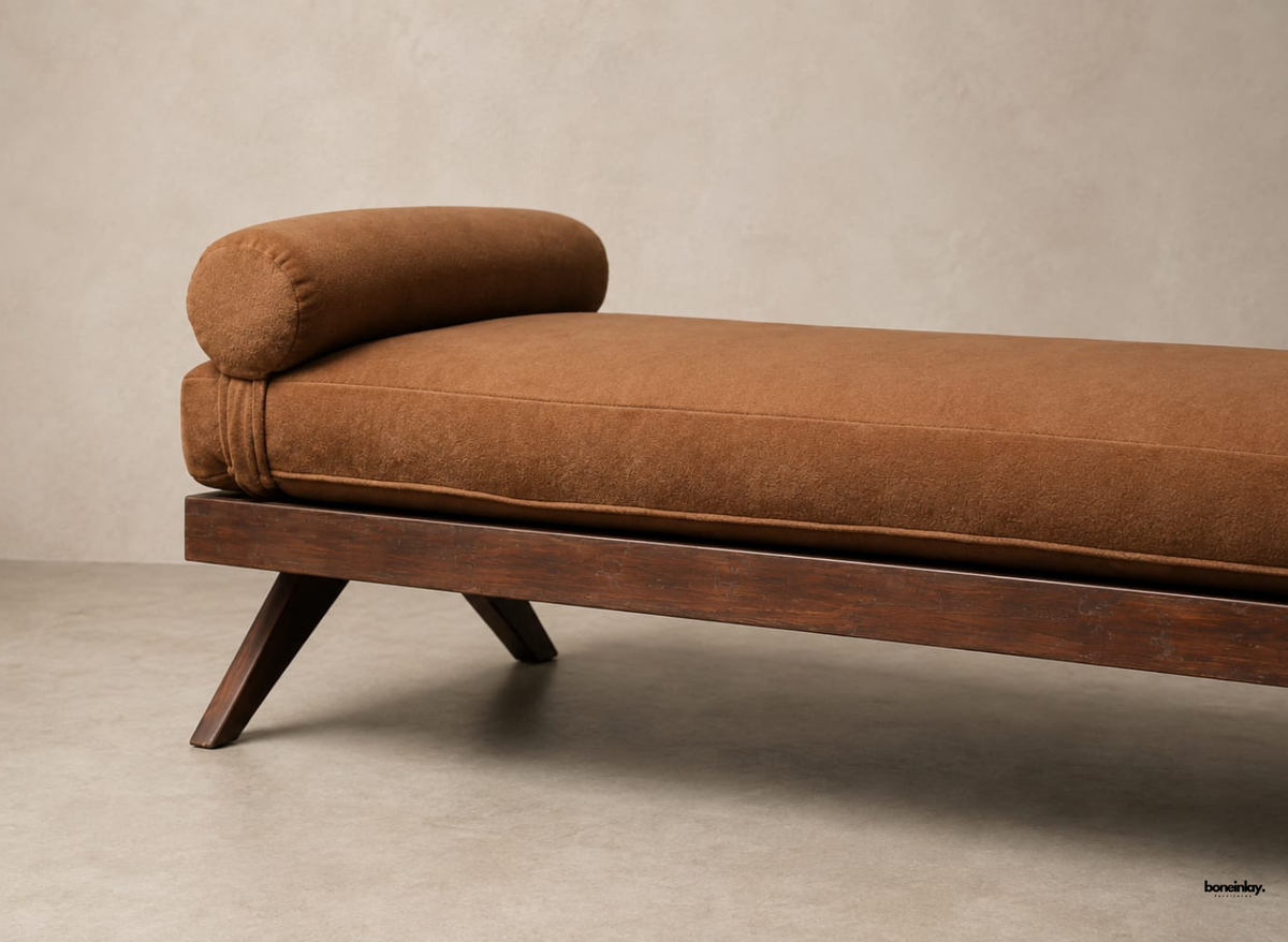 Close-up view of a handcrafted wooden daybed showcasing the smooth brown fabric upholstery, cylindrical bolster cushion, and polished dark wood frame. This stylish artisan daybed delivers contemporary elegance and relaxing comfort for modern British home interiors.