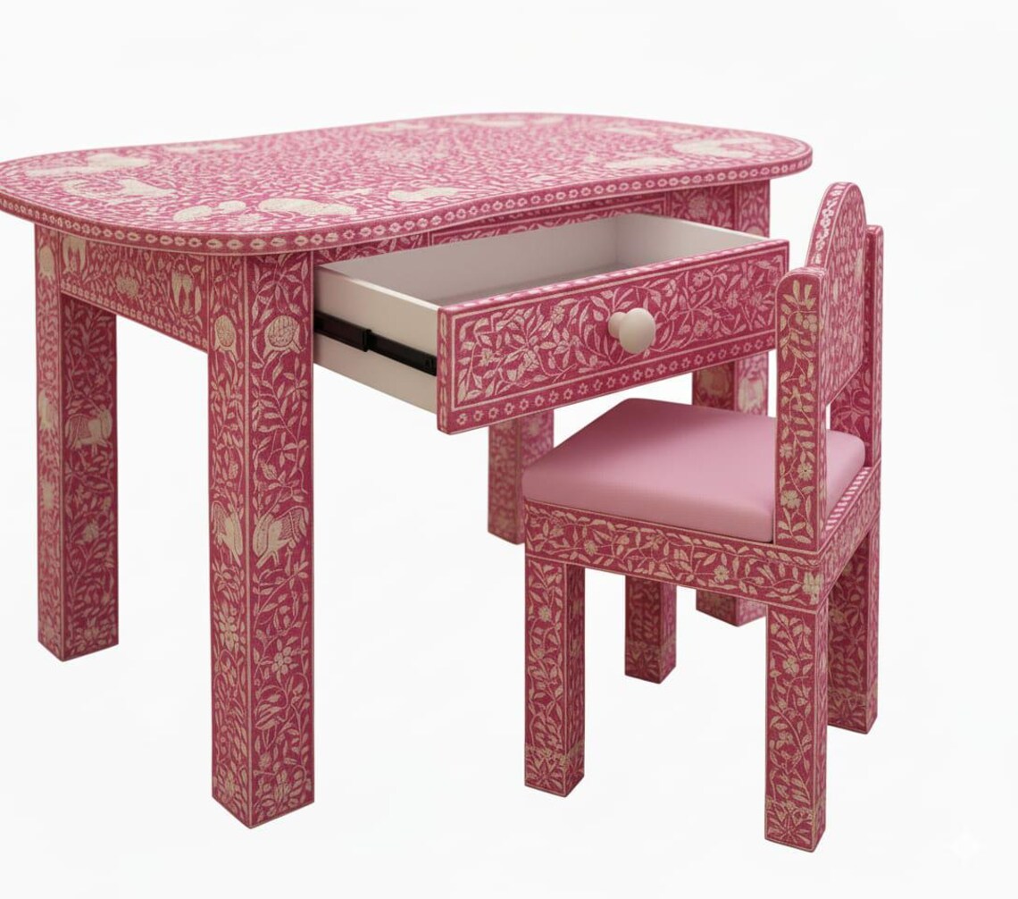 Pink bone inlay kids desk with an open drawer and matching chair with a pink seat cushion against a white background.