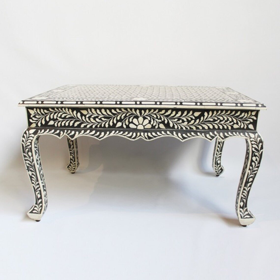 Bone inlay French style coffee table in black and white featuring all-over floral vine pattern and carved cabriole legs on white background