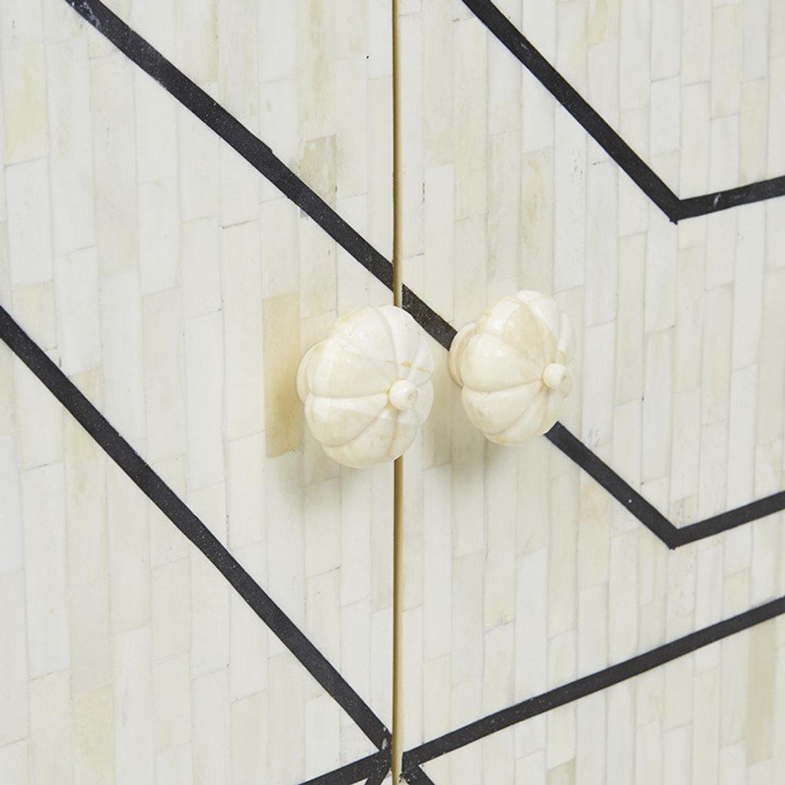 Pair of hand-carved white bone floral cabinet knobs on an ivory geometric bone inlay sideboard door with black line pattern and gold trim detail