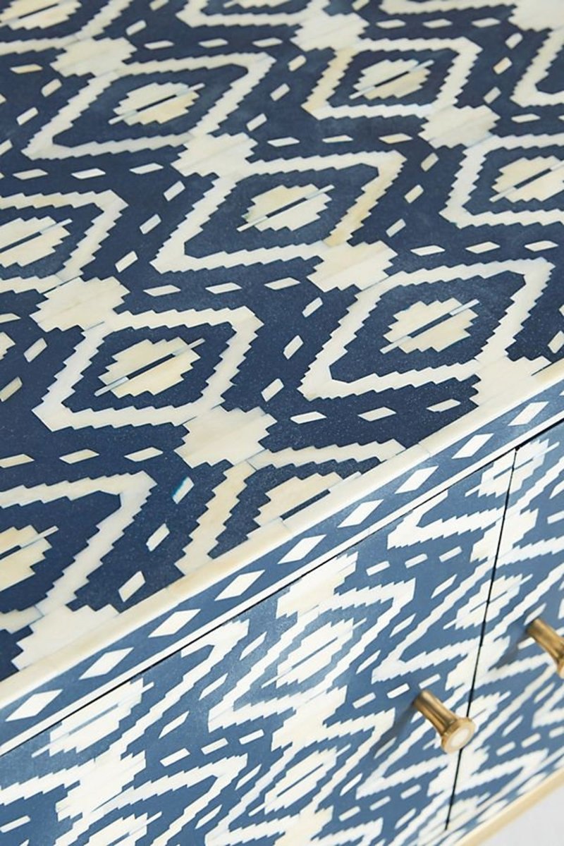 Close-up side view of the handmade indigo and cream bone inlay TV unit, showing the geometric ikat pattern continuing across the cabinet surface, clean joins along the edge, solid brass hardware, and the handcrafted placement of the contrasting inlay pieces.