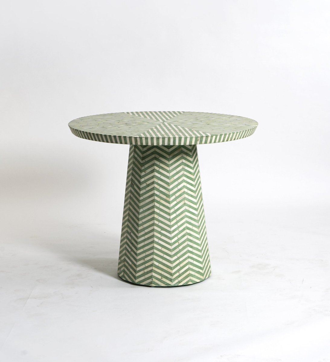 Handcrafted sage green and white chevron bone inlay round pedestal dining table on a white background, showing full table with conical base.