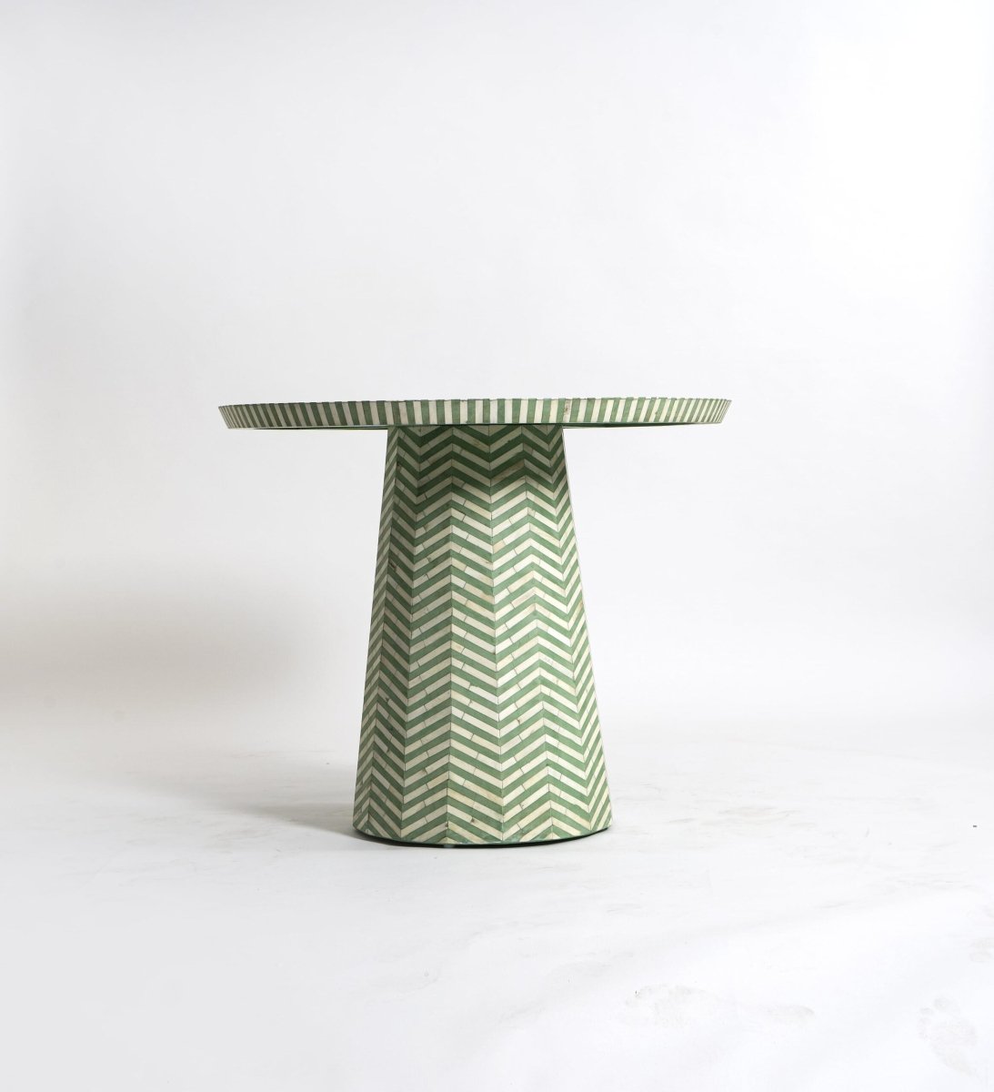 Sage green and ivory geometric chevron bone inlay accent table with a tapered pedestal base, isolated on a clean white background.