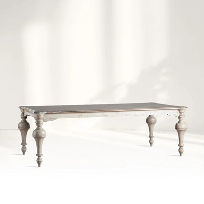 A large French Provincial style solid wood dining table with ornate hand-turned baluster legs and a distressed white-wash finish.