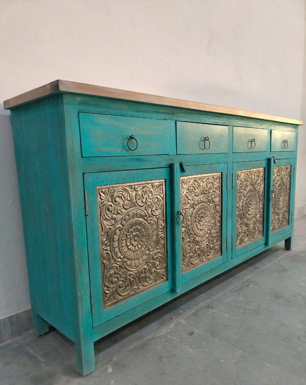 Teal four-door credenza with patterned panels, shown at an angle that reveals its long front and side profile.
