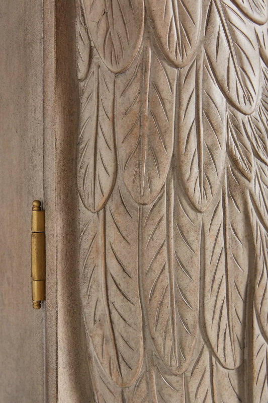 Arched Crane Armoire in a light wood finish, close-up of feather relief beside a brass hinge on the door frame.