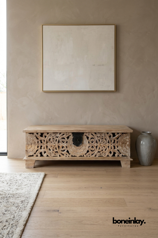 Natural wood carved trunk bench with an ornate floral scroll front.
Hand-carved vine and flower medallion covers the entire front panel.
Black metal hardware adds a rustic, antique-inspired accent.
Styled beneath a framed canvas and beside a ceramic floor vase.