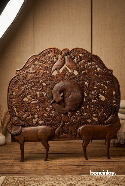Intricately hand-carved dark brown walnut wood headboard featuring detailed woodland animals like a sleeping fox, owls, and deer surrounded by forest foliage, displayed on a wooden floor.