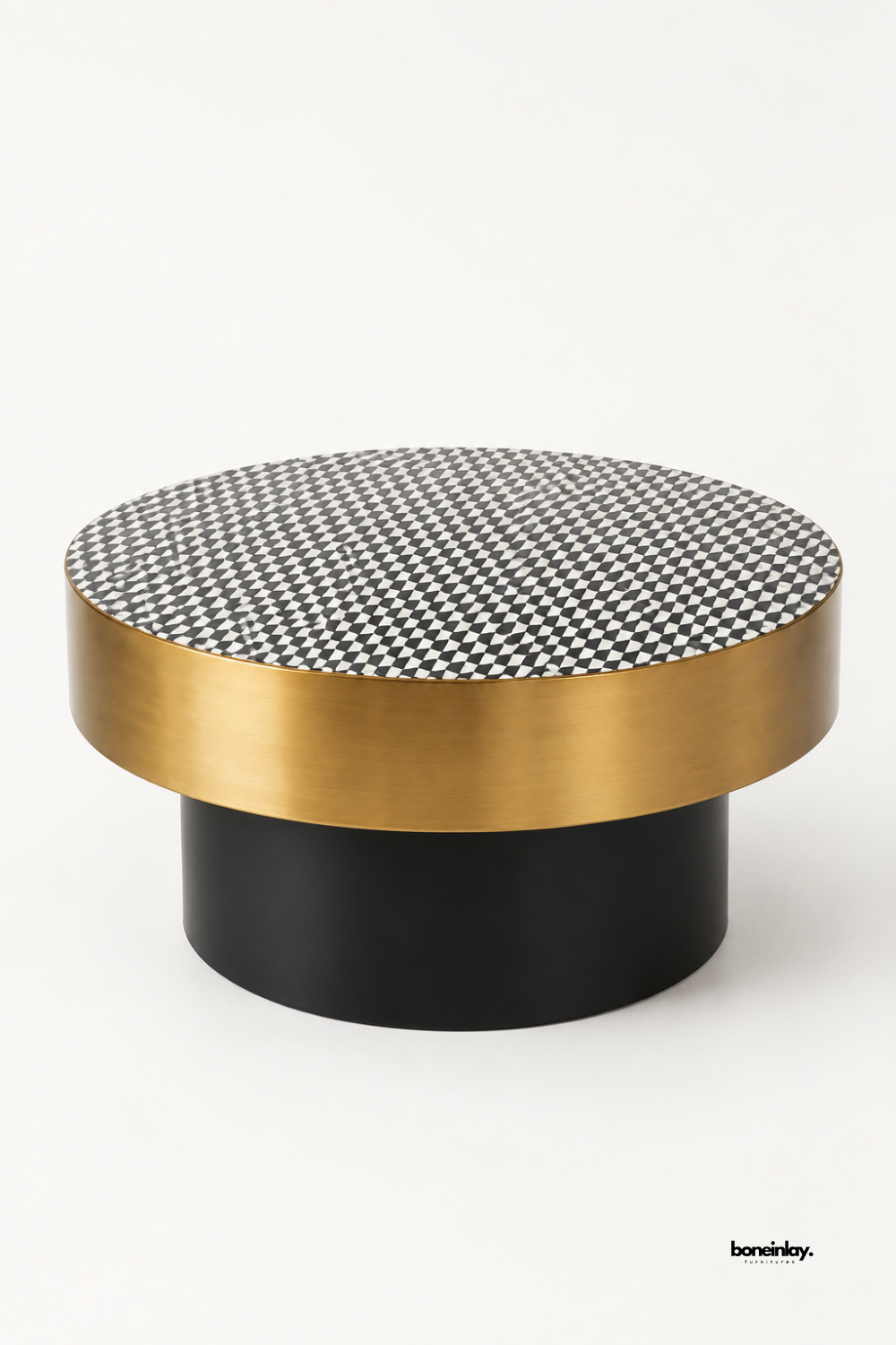 Artisan-crafted round coffee table featuring a monochrome black and white checkered bone inlay tabletop, a wide brushed brass metal apron band, and a matte black cylinder pedestal base. Showcased on a white studio background, this contemporary cocktail table seamlessly blends bold geometric art with modern metallic elegance.