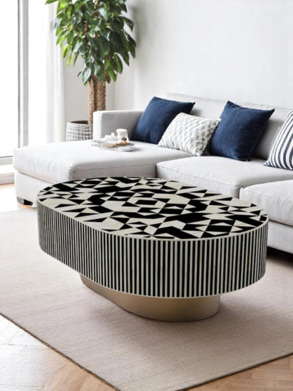 Black and white bone inlay oval center table with striped sides placed in a bright modern living room with navy sofa