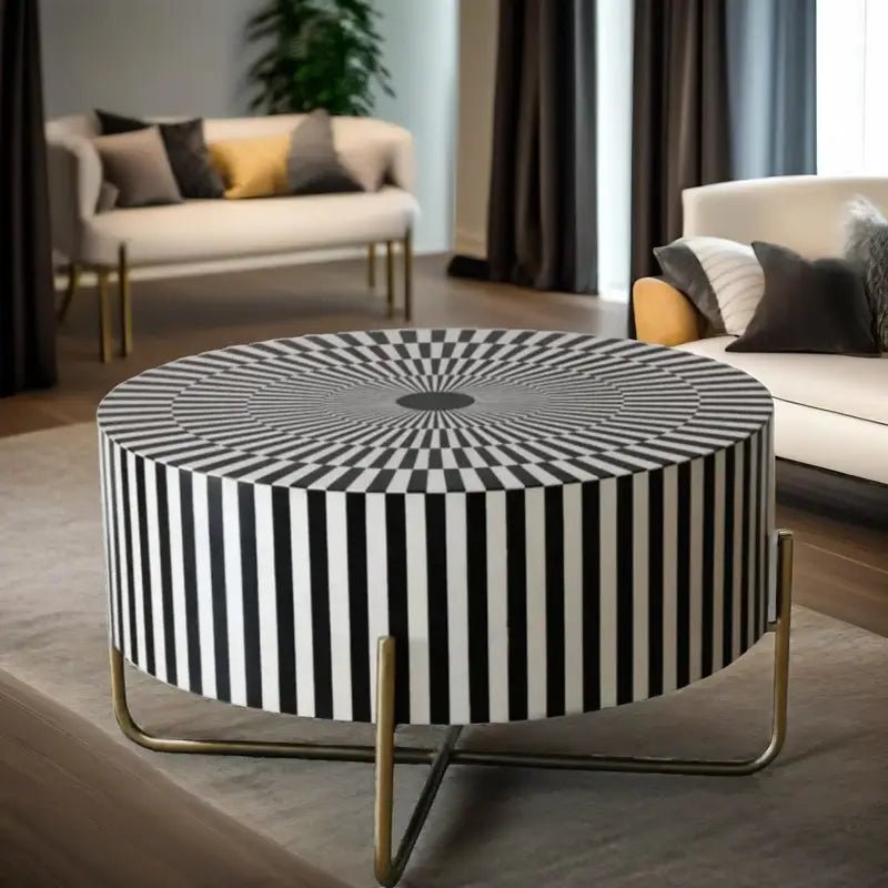Round bone inlay coffee table with an optical radial stripe design in black and white, supported by a sleek gold metal base, placed in a contemporary living space