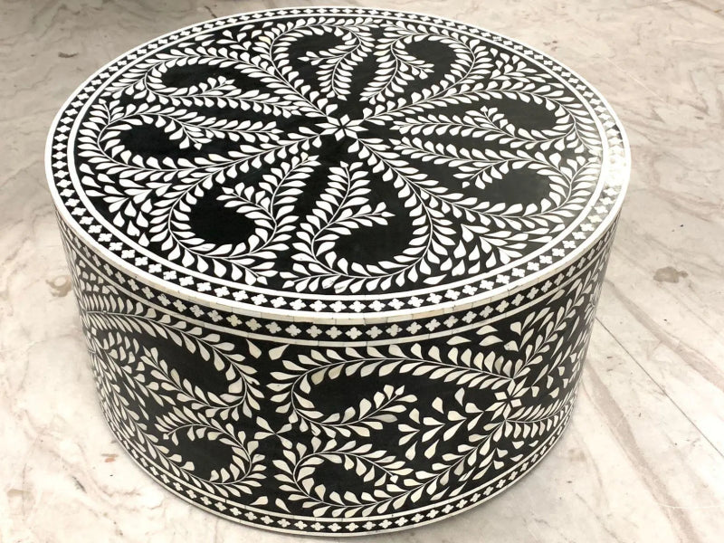 Black and white bone inlay round drum coffee table with all-over hand-carved floral vine and leaf pattern on top surface and cylindrical body, handcrafted from mango wood.