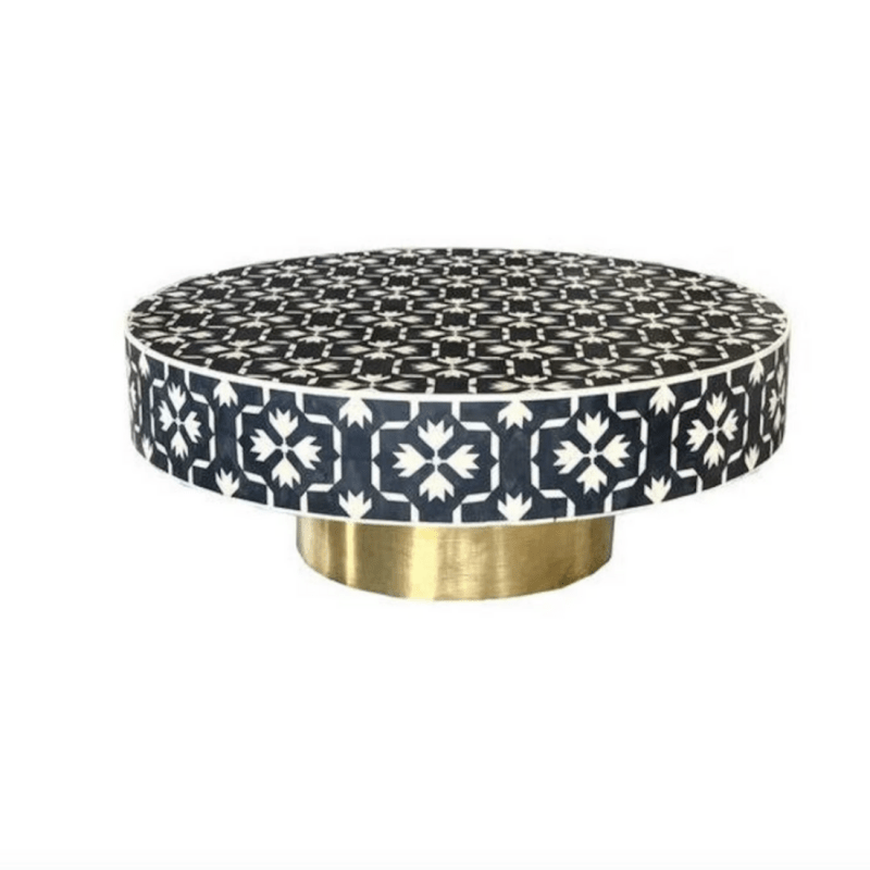 Round bone inlay coffee table featuring bold black and white geometric floral mosaic pattern on solid mango wood with a shiny brass circular base, product shot on white background