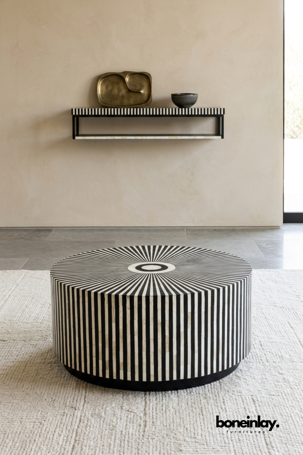 Black and white bone inlay drum coffee table with sunburst top, styled in a living room beneath a matching wall shelf.