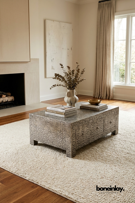 Rectangular grey coffee table with storage drawers and intricate floral pattern placed on a cream area rug