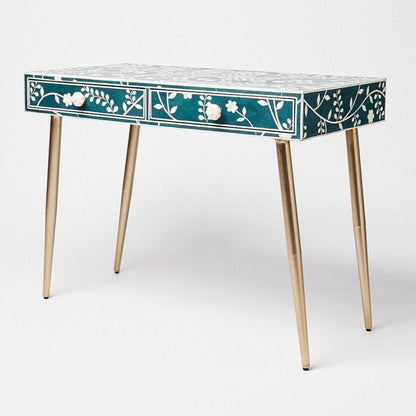 Blue bone inlay floral dressing table with two drawers, white floral vine pattern on teal surface, carved flower drawer knobs, and gold-finished tapered metal legs on white background