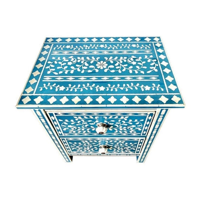 Isolated top surface of a teal blue bone inlay nightstand featuring hand-laid white floral wreath center, leafy vine border rows, and diamond tile border on all four edges.