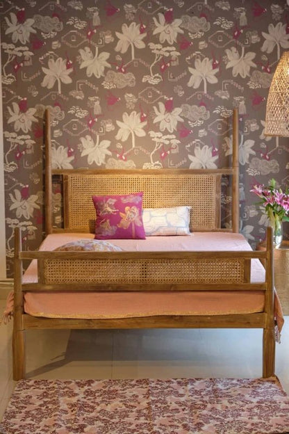 Bohemian-style wooden bed with cane detailing and tall corner posts.