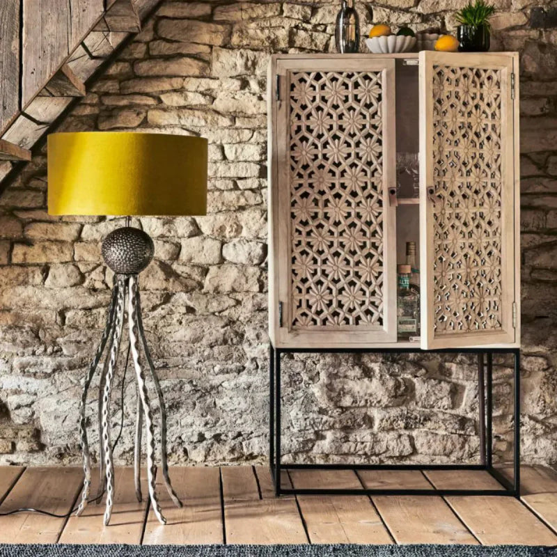 Sand washed wood cupboard with carved lattice doors, styled in a living room with an exposed brick wall.