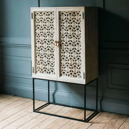 Bohemian lattice liquor cabinet in light sand-washed finish with carved doors, shown in a front view.