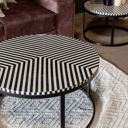 Bold chevron stripe bone inlay round coffee table with black metal frame, luxury handmade monochrome center table shown in a modern living room interior