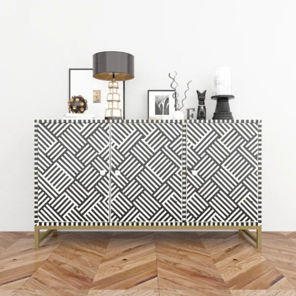 Bone inlay charcoal grey and white geometric sideboard cabinet styled with table lamp, photo frames and decorative objects on herringbone wood floor