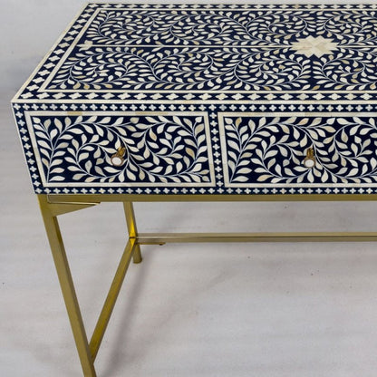 Blue bone inlay console table showing full floral vine surface inlay, two drawer fronts with brass knobs, and gold cross-base metal legs